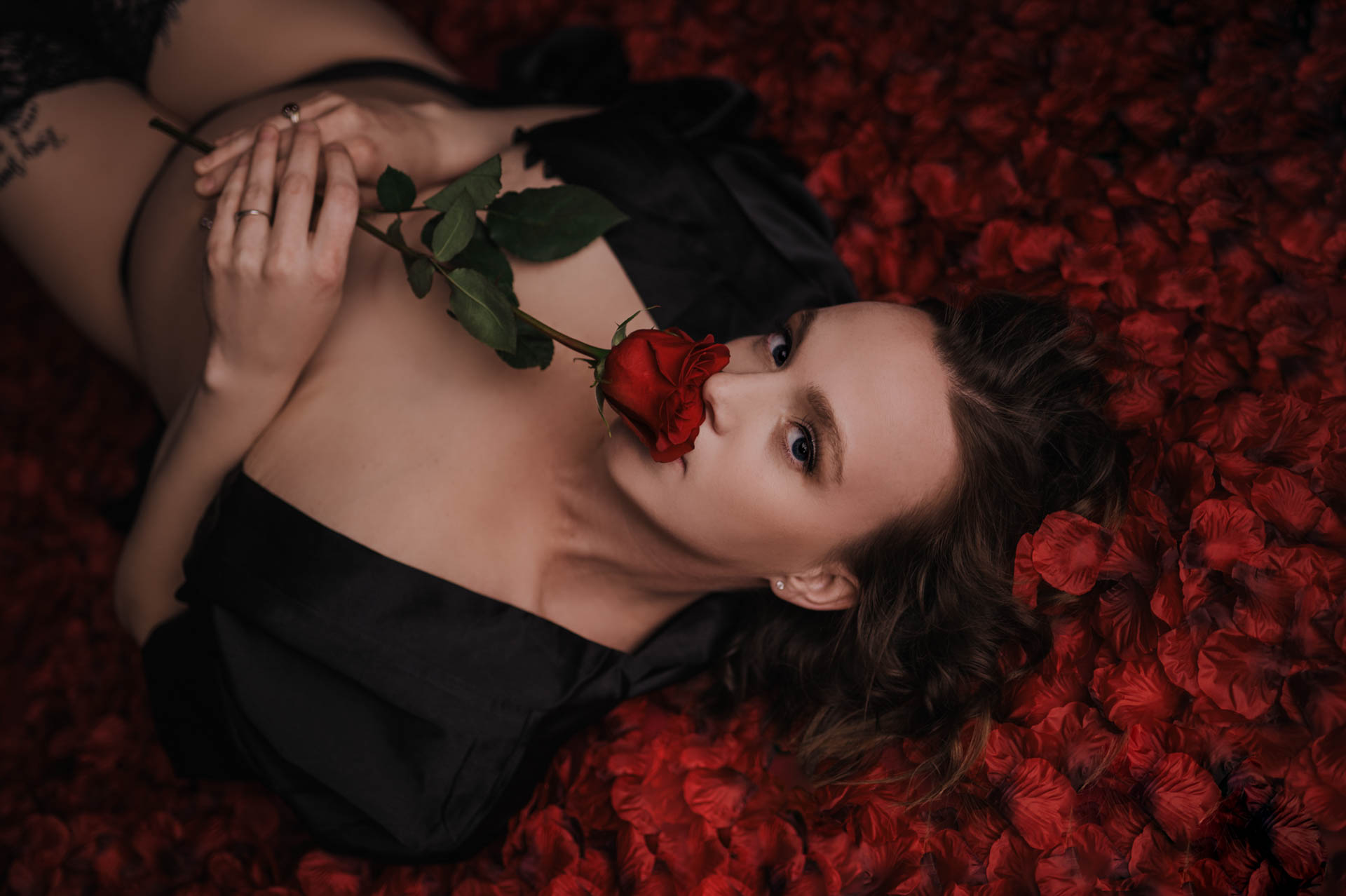woman posed on a bed of rose petals for boudoir photography